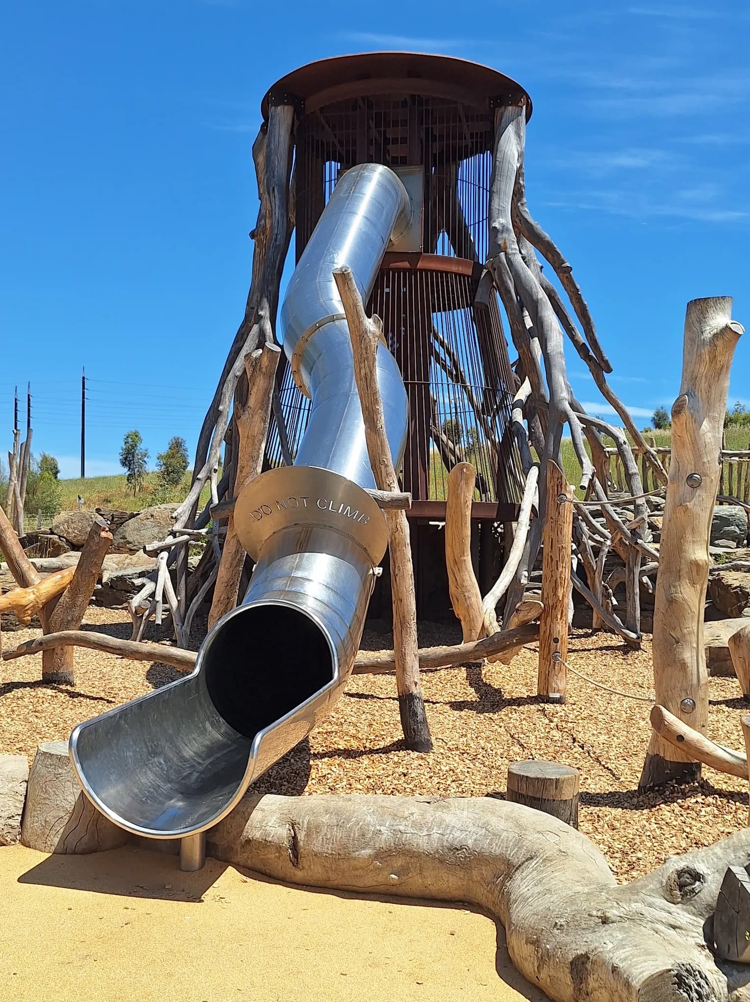 Natural timber playground tower with a stainless steel tunnel slide
